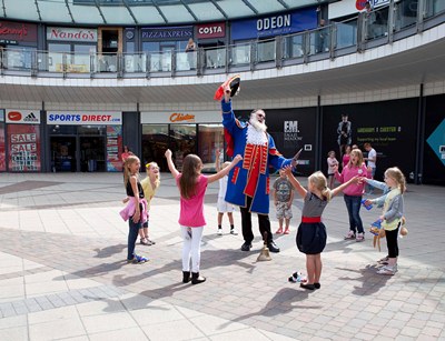 The World's tallest Town Cryer Martin Wood officially announces the start of Wrexham's Year of Culture Street Entertainment Festival Competition at  Eagles Meadow in Wrexham. Pictured: Martin Wood attracts the attention of a group of youngsters on their way to a party